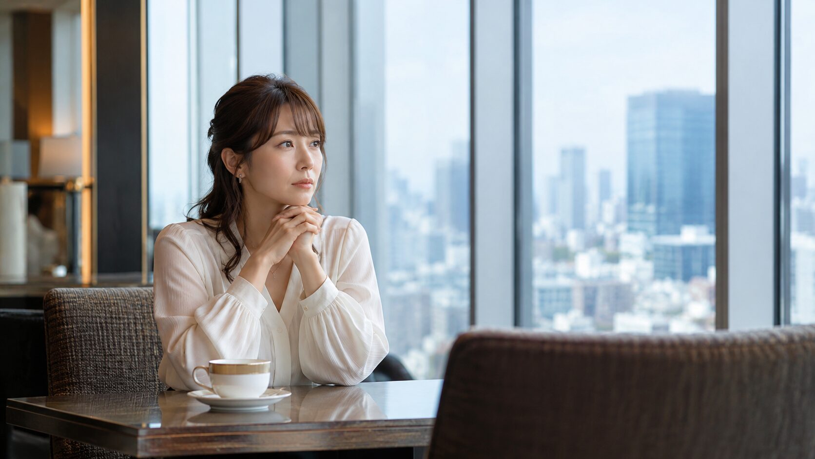 高級ホテルラウンジで向かい側の空席を見つめる日本人女性。婚約者が勤務先を教えてくれないことへの違和感や、結婚前に相手を知りたい気持ちを象徴的に表現した写真風イメージ。婚前調査に関する記事のアイキャッチ画像。
