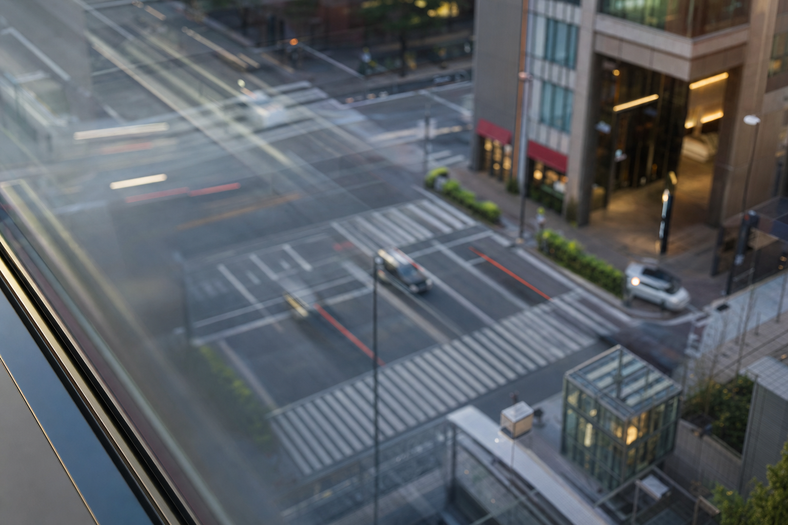 東京都心の交差点をビル高層階から見下ろす夕景。行き交う車と人の流れがぶれて写る 東京都心の交差点をビル高層階から見下ろす夕景。行き交う車と人の流れがぶれて写る